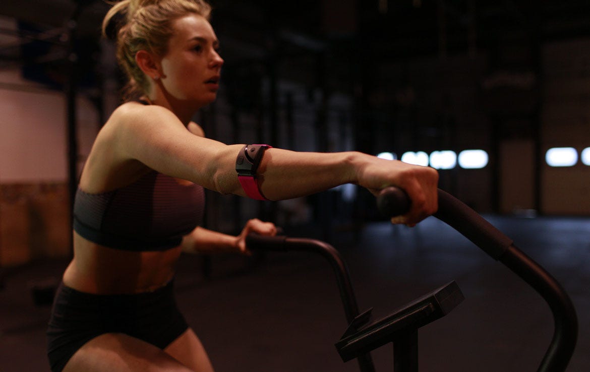 woman on elliptical wearing pink armband heart rate monitor