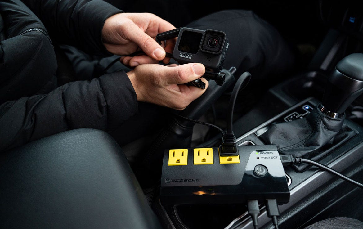 man chargina GoPro camera using power inverter in car