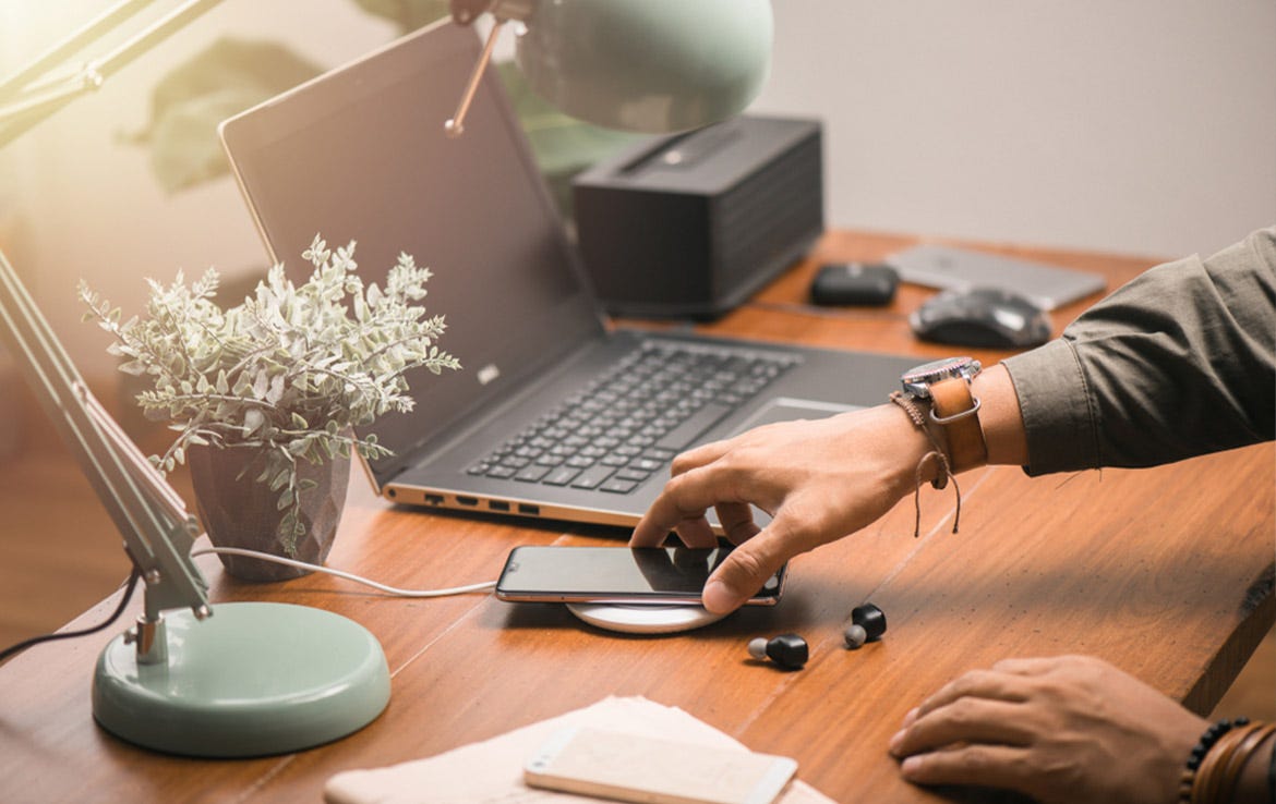 man at desk charging phone via wireless charger