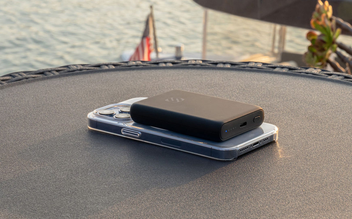 iphone charging via Scosche portable power bank sitting on table at waterfront