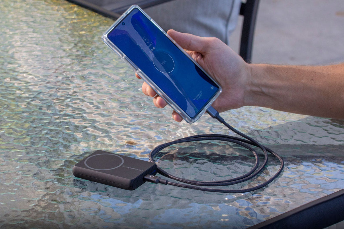 phone charging via Scosche portable power bank on glass table