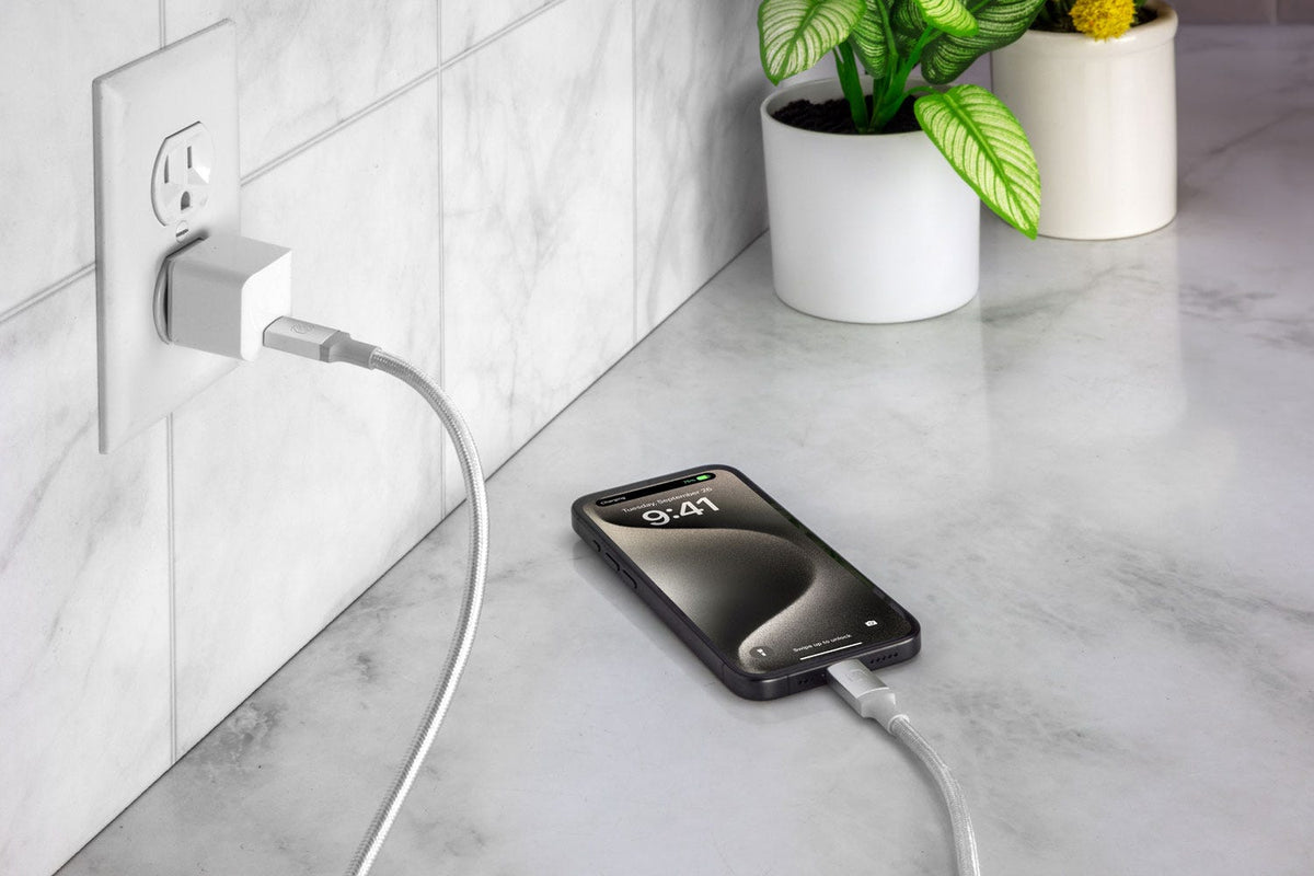 iphone charging via Scosche braided charging cable plugged into 60 watt wall charger while sitting on counter
