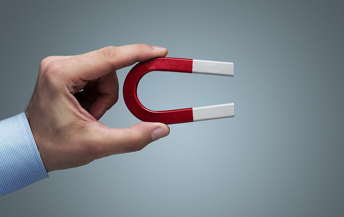 man holding red and silver magnet between thumb and index finger