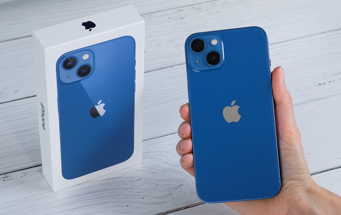 man holding blue iphone 13 next to box