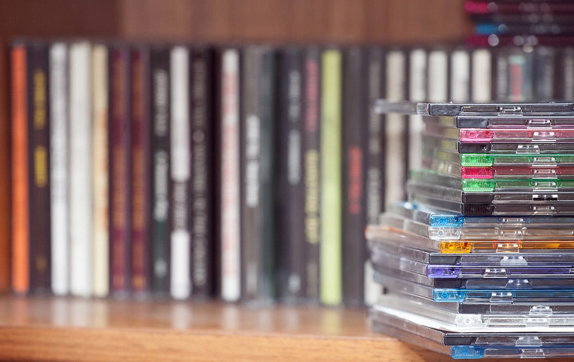 side of stacked CDs with DVDs in background