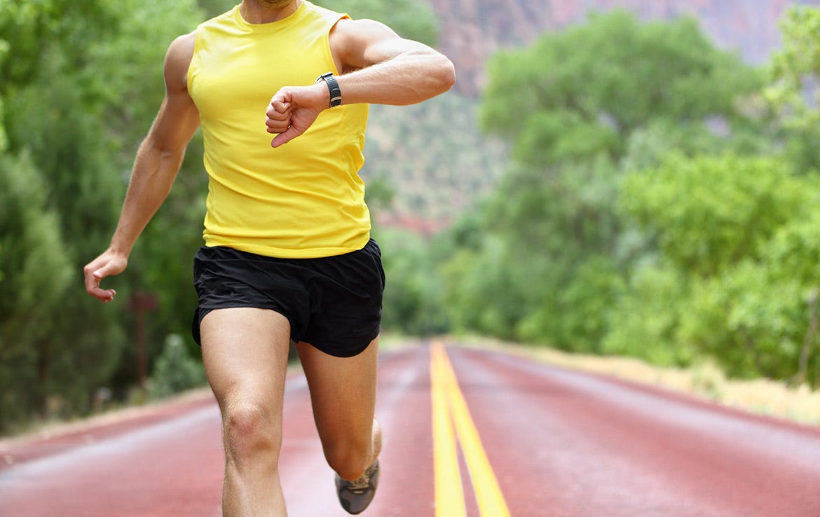 man running on street and checking watch for heart rate