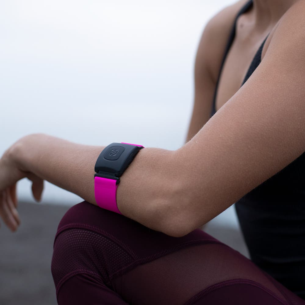 woman kneeling and wearing Scosche armband heart rate monitor