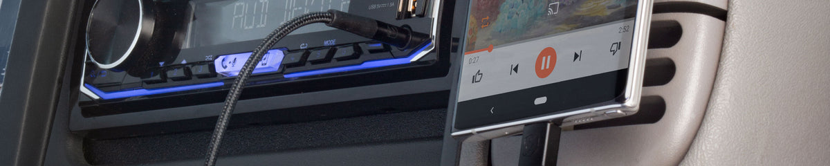 Close up of a USB-C cable plugged into a phone and connected to a car stereo AUX port