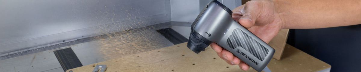 Hand holding portable duster blowing saw dust off a band saw