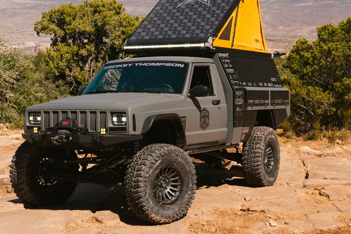 Heavily modified Jeep Commanche with overlander tent up on the back in the desert