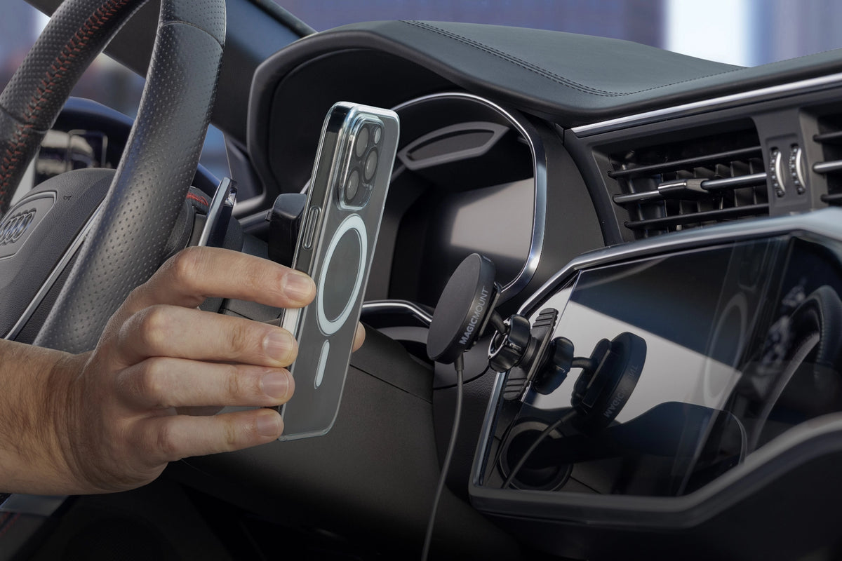 Hand holding phone up to wireless charging magnetic phone mount attached to vehicle console