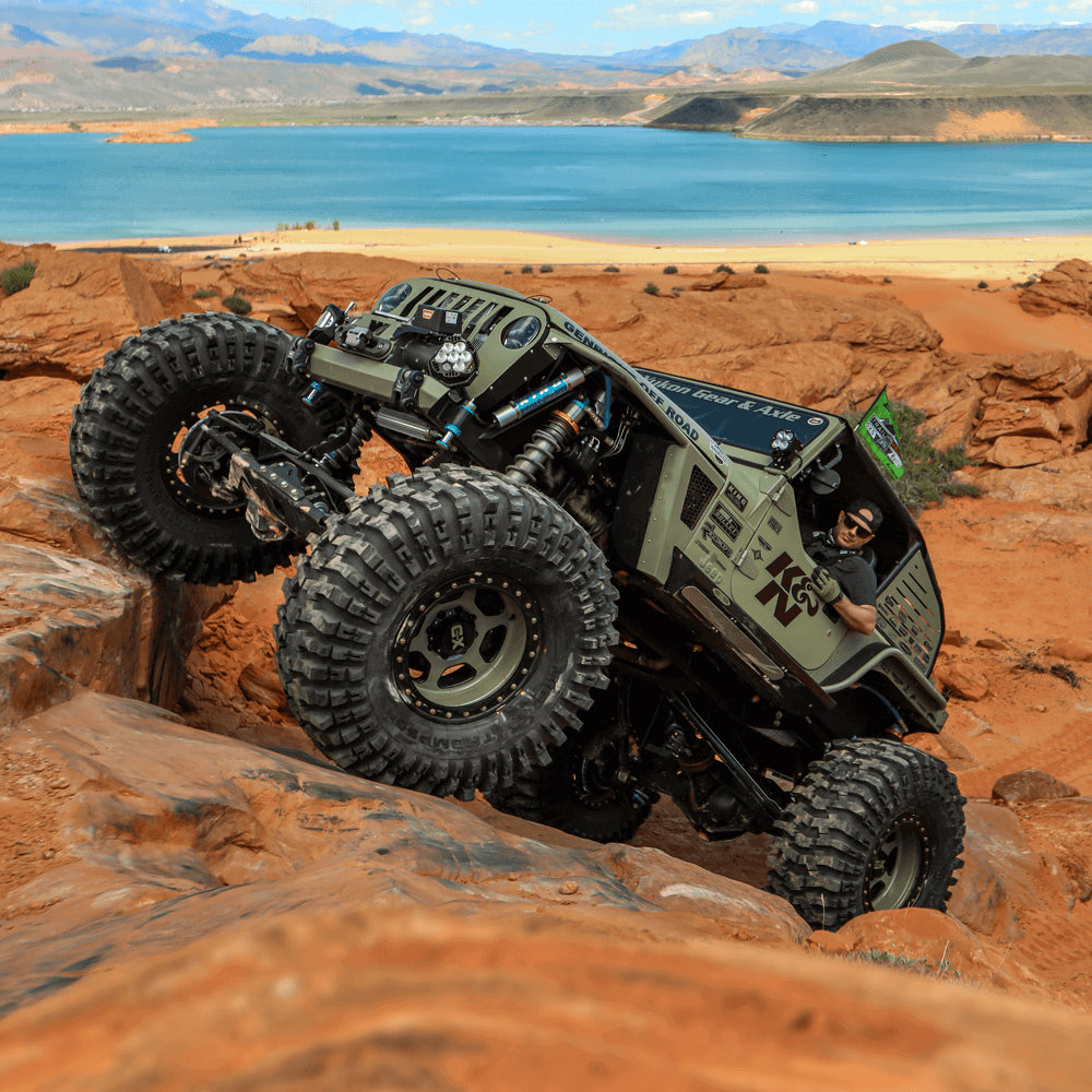 Modified Jeep Wrangler driving up steep rocks in the desert