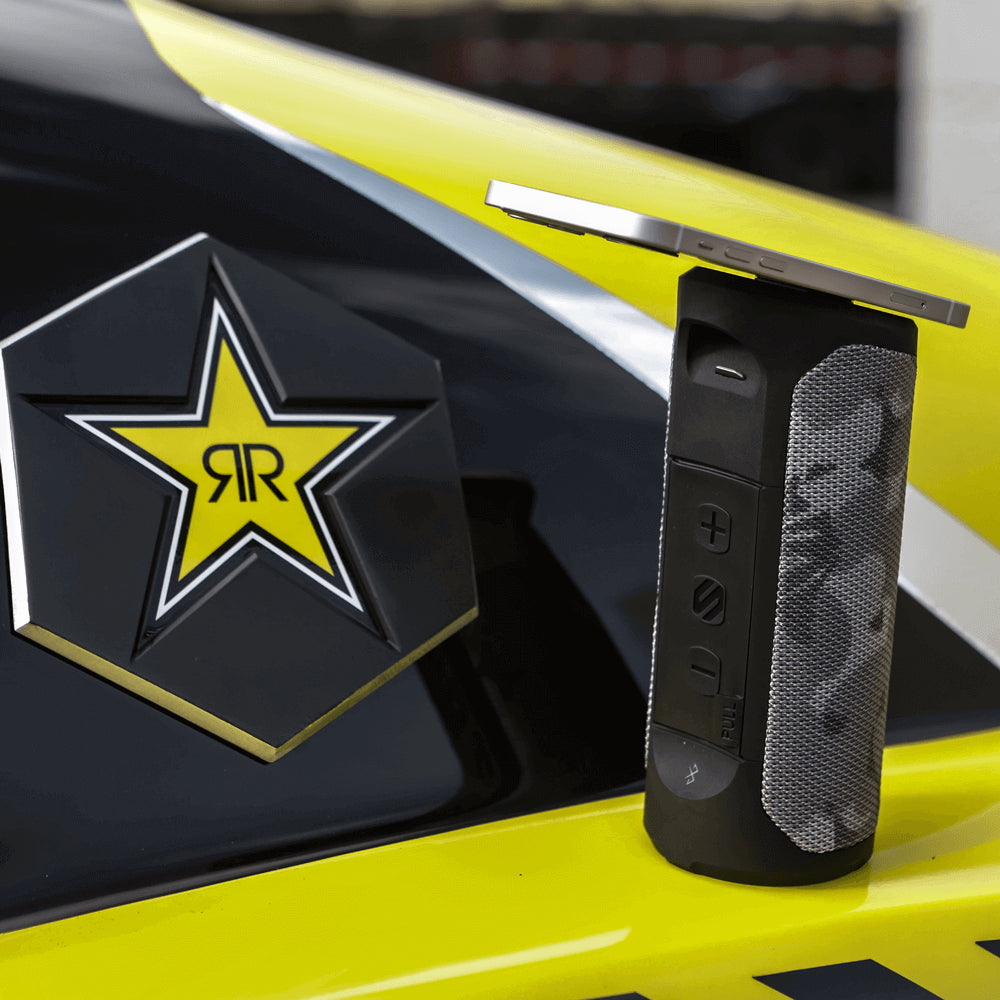 Bluetooth speaker with phone magnetically attached to top on side of vehicle with Rockstar Energy logo on it