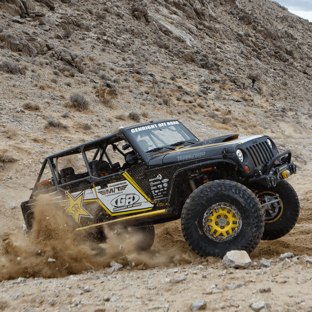 Modified Jeep Wrangler kicking up dirt and rocks will driving offroad
