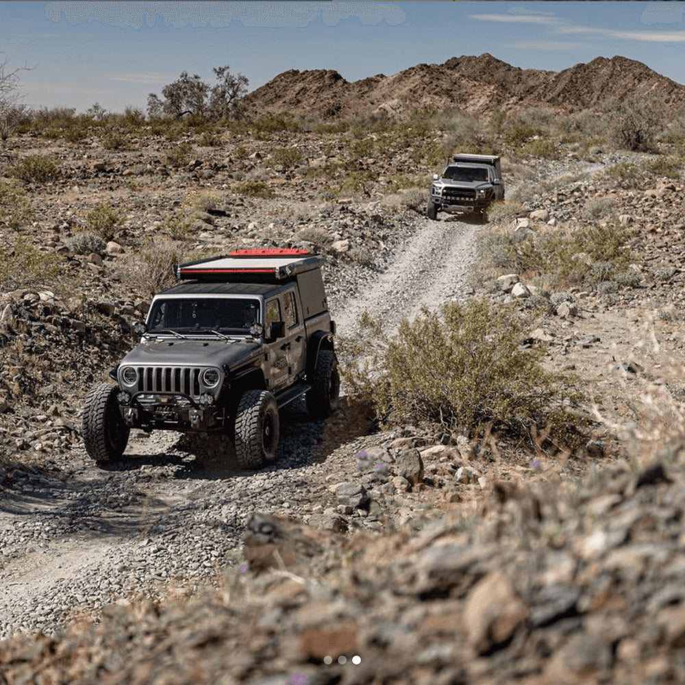 A custom Jeep an Tundra drive through the desert on a rocky road