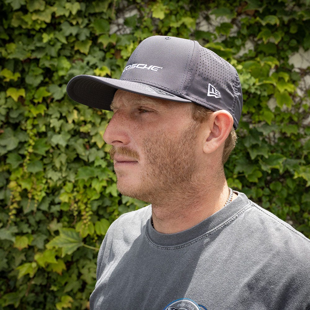 side view man wearing gray hat with bush in background