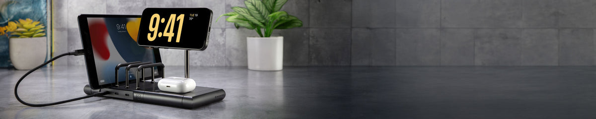 Black charging station on a countertop with an iPhone, iPad and AirPods on it