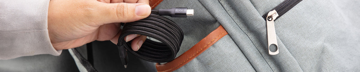 Hand inserting a coiled cable into a backpack pocket