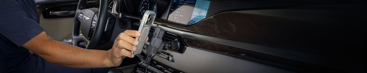 Arm of a man holding a phone up to a phone mount on a vehicle dashboard