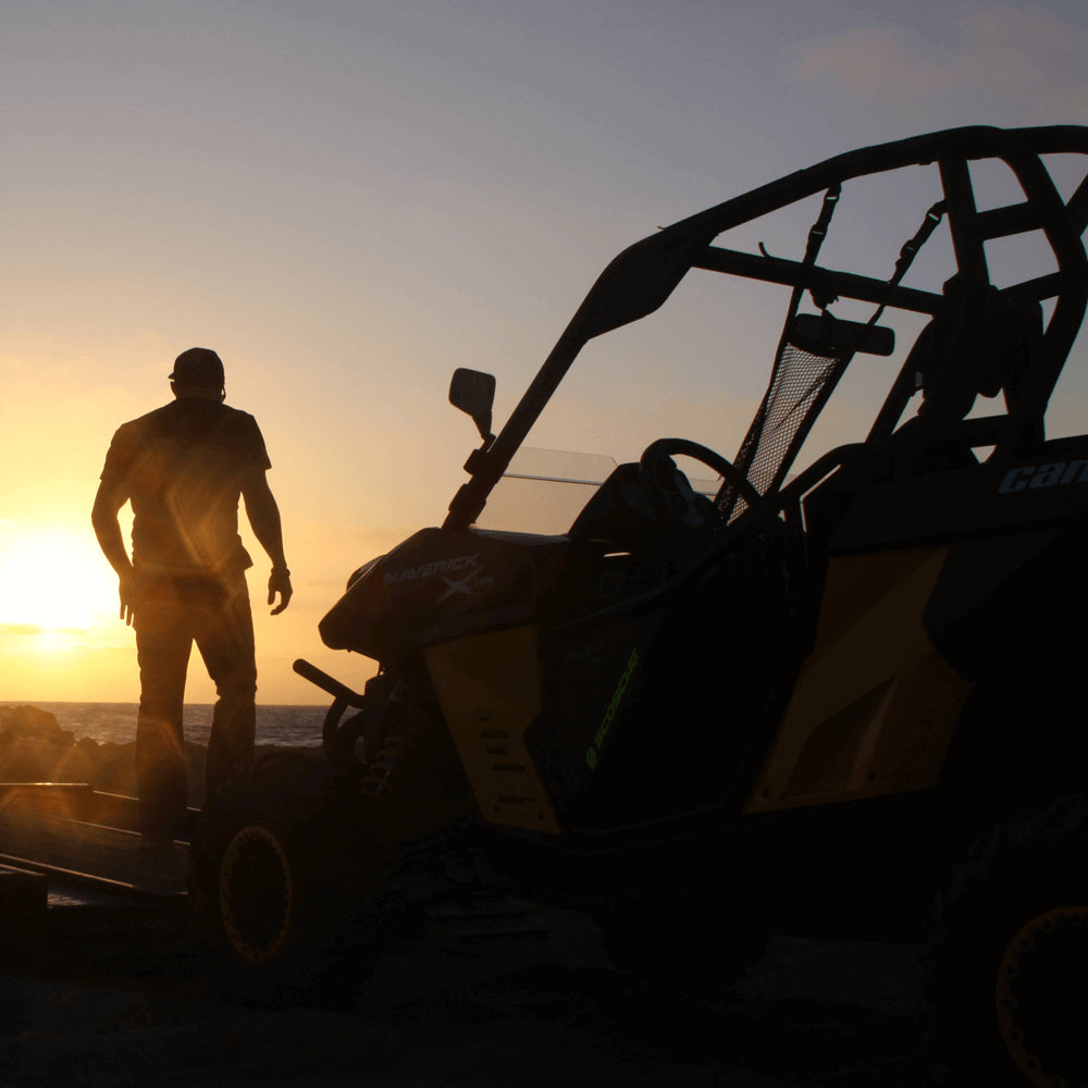 Silouette of man standing next to off road vehicle at sunset
