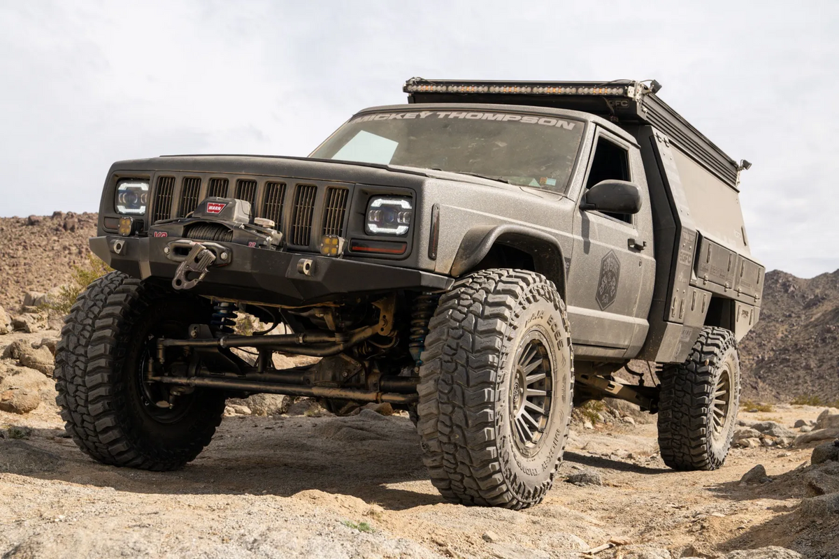 Heavily modified Jeep Commanche driving on dirt path in the desert