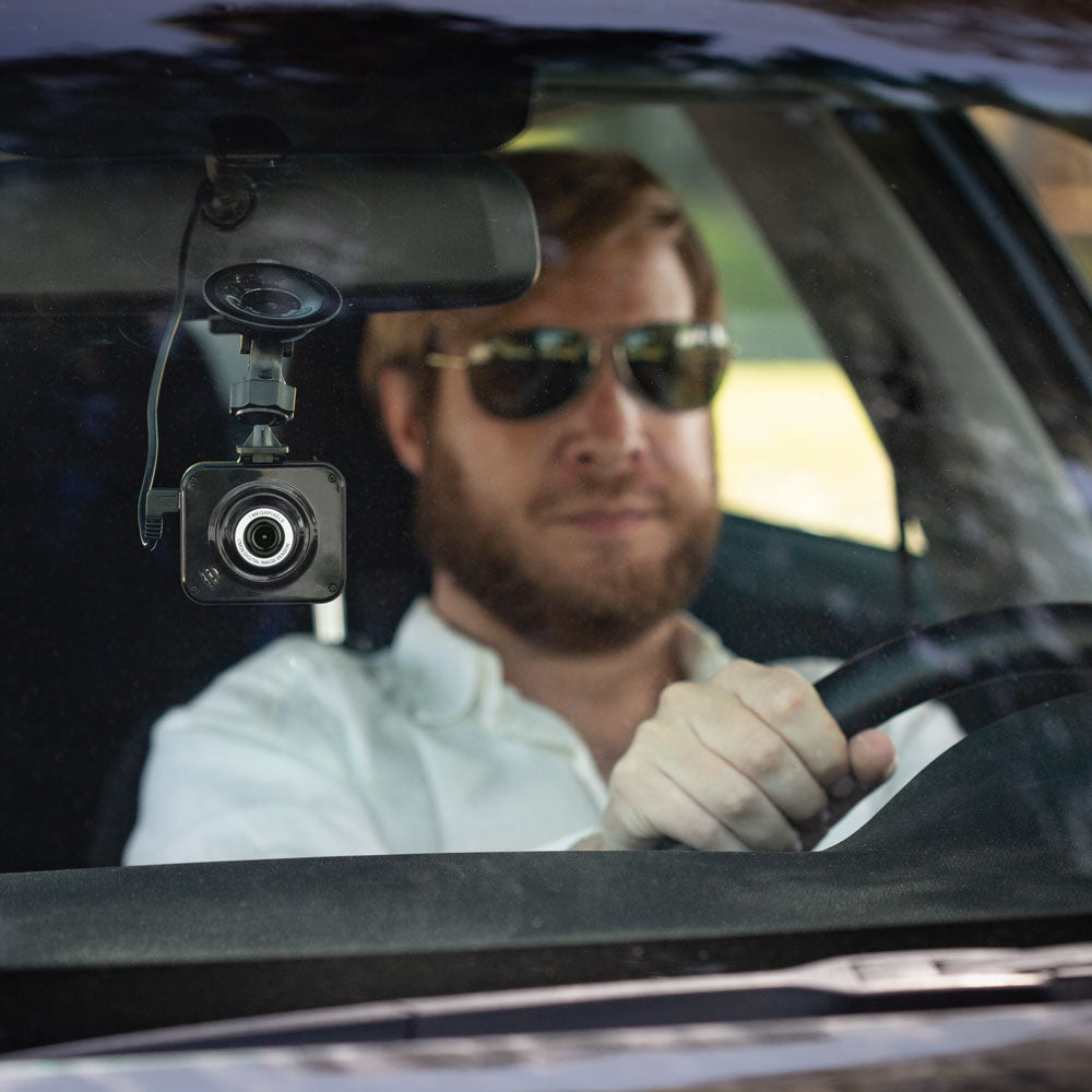 Man with beard driving with dash cam on windshield