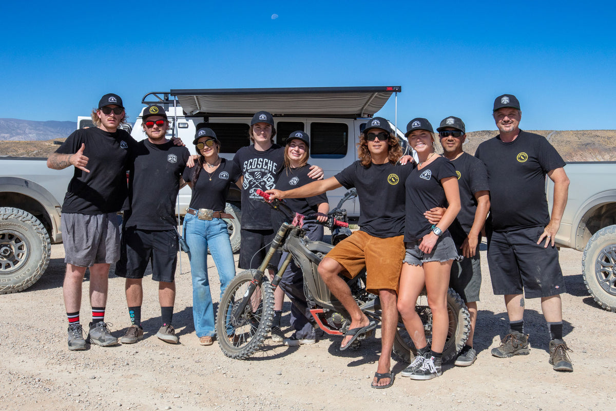 Group photo in desert with show vehicles behind