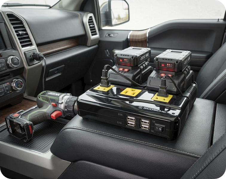 Image of an inverter set inside a vehicle charging batteries with a power tool next to them