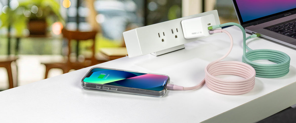 iPhone and MacBook plugged into a single charger connceted with pink and green cables