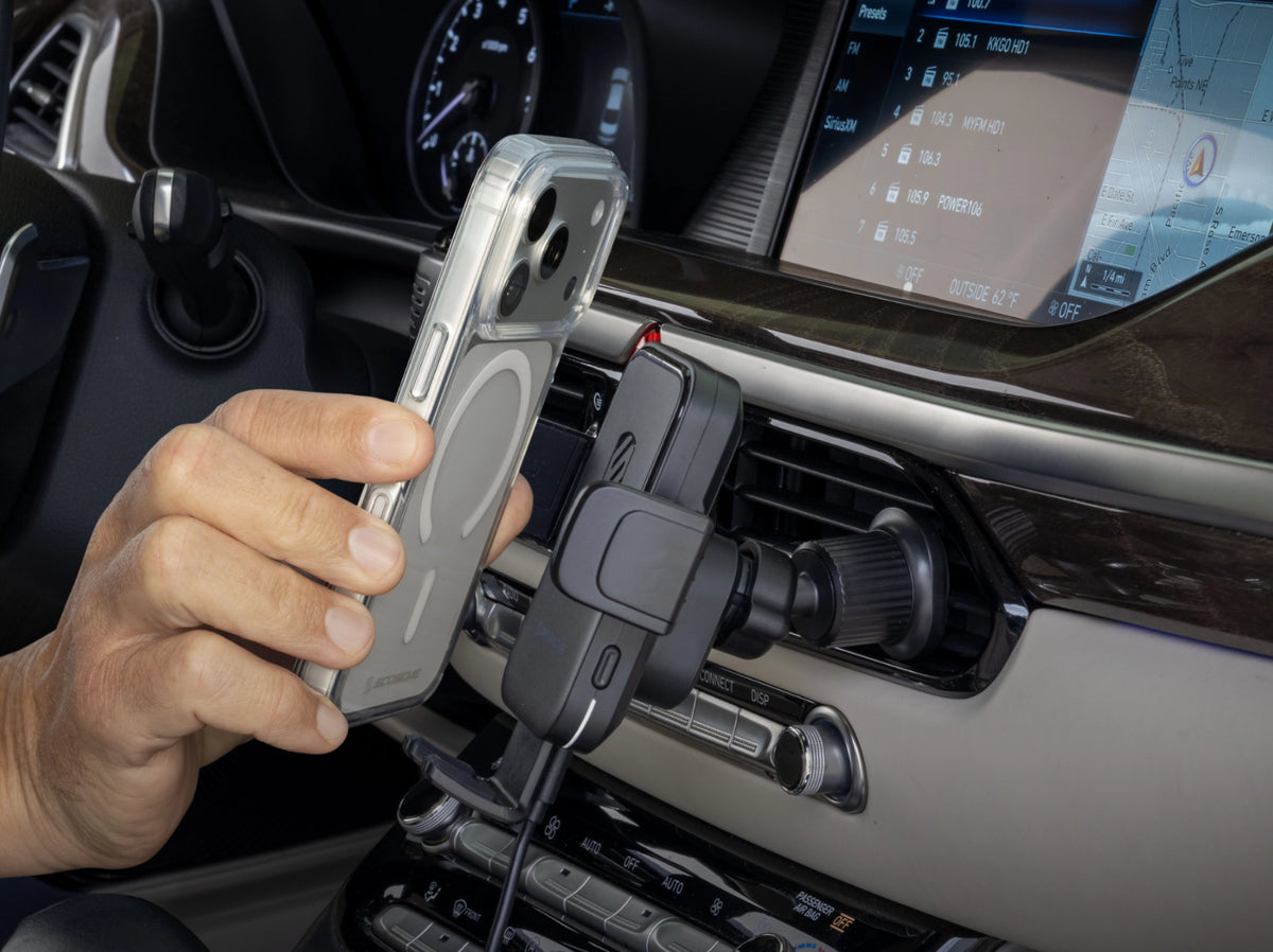 Image of a hand placing a phone into the cradle of the phone mount, inside a vehicle
