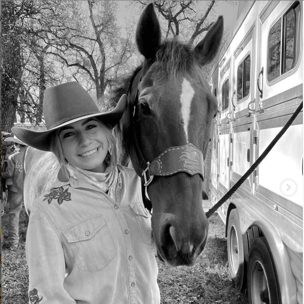 Skyler and her horse smile for a photo with their horse trailer in the background