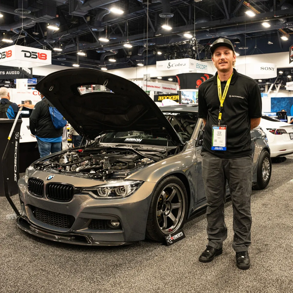 Man standing next to BMW with hood opened at tradeshow