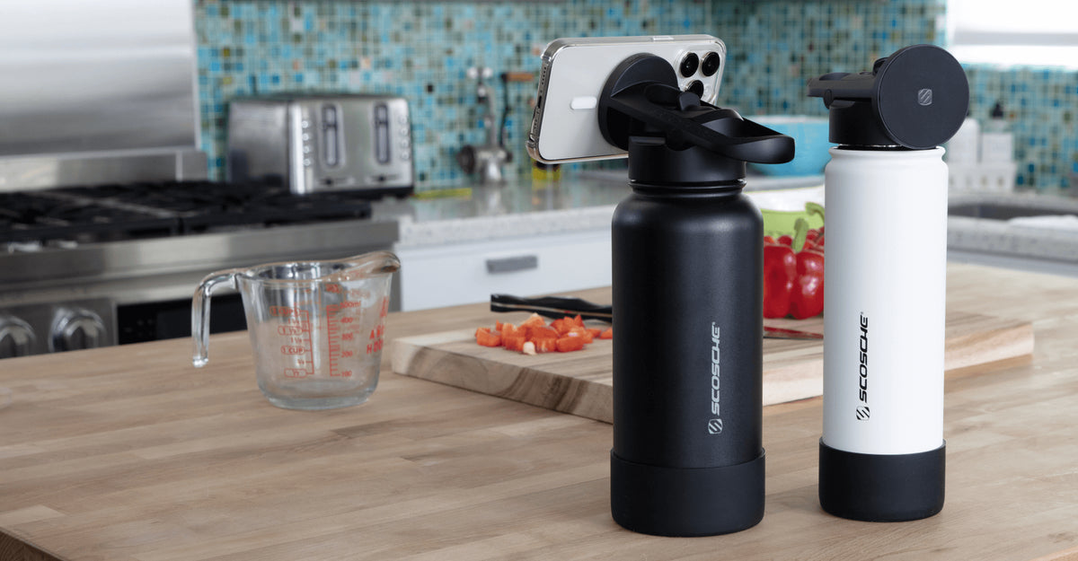 Image of the 22oz white Flask and the 32oz black Flask with a phone attached to the magnetic cap, on a kitchen counter