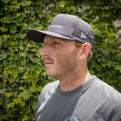 side view man wearing gray hat with bush in background